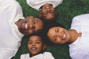como-educar-seus-filhos-familia-feliz-deitada-na-grama